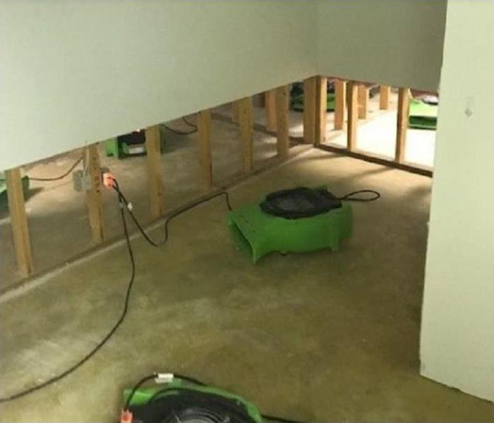 Flood cuts along water damaged wall; SERVPRO restoration equipment being used to dry rooms
